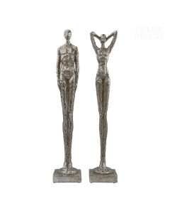 Dekor Deluxe set dveh ločenih podolgovatih srebrnih skulptur moškega in ženske z izrazito dolgimi nogami na podstavku v obliki kvadra.