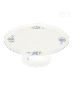 Dekor Deluxe krožnik za torto bele barve iz vrhunskega porcelana z nežno poslikavo s spominčicami.