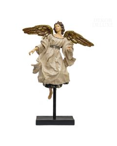 Ženski angel z rjavimi lasmi, zlatimi krili in bež haljo v letečem položaju na črnem masivnem podstavku.