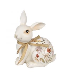 Figura belega velikonočnega zajčka z mašnico in z rožicami poslikanim telesom. 